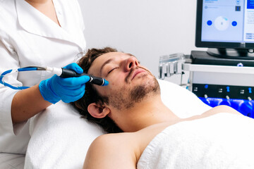 Man undergoing a facial peeling procedure in a beauty clinic, close-up. Rejuvenating hydro-air skin...