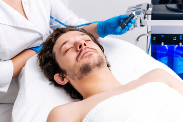 Man in a cosmetic clinic undergoing facial cleansing and rejuvenation treatments. Premium skincare technologies for radiant, refreshed skin. Perfect for promoting salon services and advanced skincare.