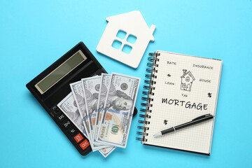 Mortgage. Calculator, dollar bills, house figure and notebook on light blue background, flat lay