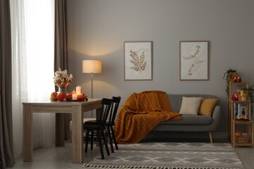 Obraz premium Burning candles and stylish furniture in cozy room. Autumn atmosphere