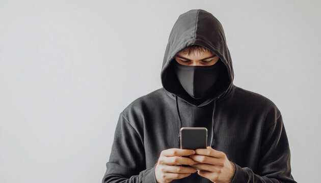 Hacker wearing a black mask and using a smartphone