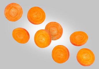 Round carrot slices in air on grey background