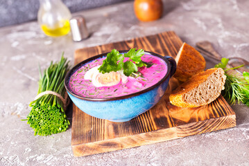 Traditional east european soup. Cold summer soup of beets, kefir, cucumbers, eggs and dill in a blue bowl closeup.