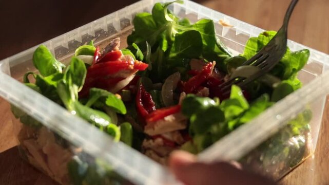 Big close-up of woman hands stirring a tupper salad in rustic kitchen. Real people. Healthy food.