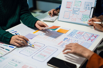 ui designer brainstorming about mobile app interface wireframe design with customer breif and color code at office.