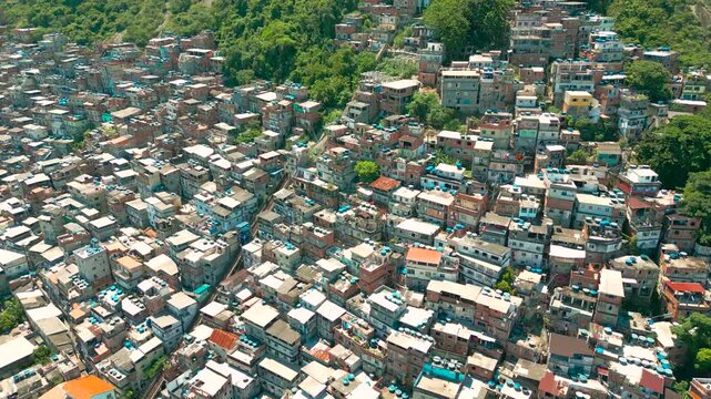 Aerial view of a densely packed hillside favela with colorful homes and lush greenery in Rio de Janeiro.