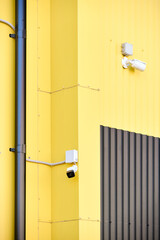 CCTV camera. Security camera on Aluminum composite panels for repair restore facade of commercial building warehouse barn wall, two CCTV on buildings monitoring the street.