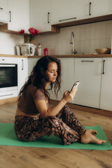 Beautiful Girl Using Smartphone after Fitness Workout at Home. Determined Plus Size Woman Using Fitness Tracker, Yoga Exercises Application, Browsing Online Health Articles, Posting on Internet