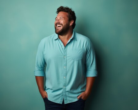 Handsome young plus size man laughs against a plain background. Diversity and self-acceptance