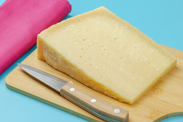 morceau de fromage Grana Padano, en gros plan, surune planche à découper