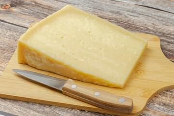 morceau de fromage Grana Padano, en gros plan, surune planche à découper