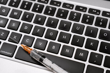 Syringe on Computer Keyboard. Technology and Healthcare.