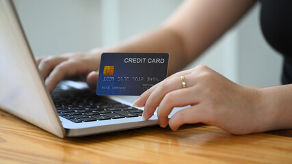 Woman holding a credit card and using laptop, e-commerce and digital payments concept