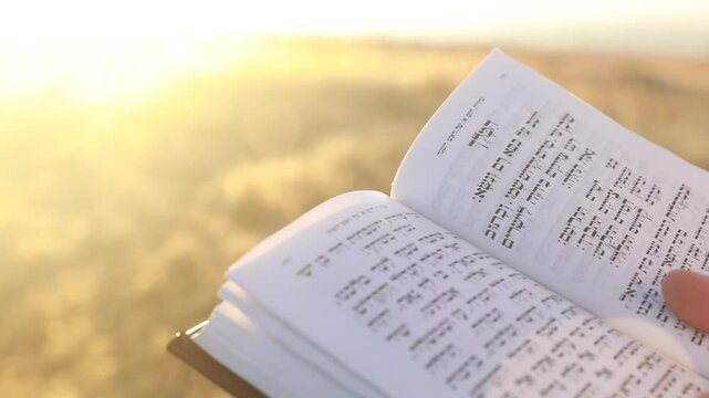 A man's hand flips through a Rosh Hashanah and Yom kippur prayer book, sidur.