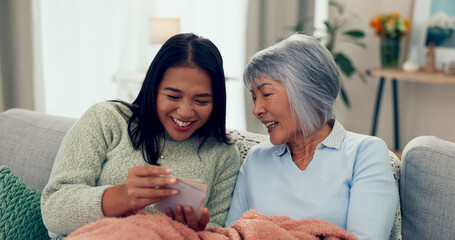 Senior mom, daughter and happy with photo album at home with laugh on sofa in living room. Retirement, pensioner and smile as parent with bonding, memories and support for unity, love and nostalgic