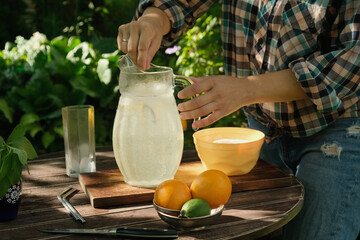 Person making lemonade drink outdoors.