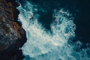 Obraz premium Rough waves crash against the rocks on the shore, creating foam and spray.