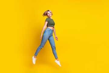 Full size photo of adorable gorgeous girl dressed khaki crop top jumping near empty space promo...