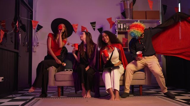 Asian friends, middle-aged man and young woman, enjoy Halloween office party with vampire costumes, fried chicken, grilled food, grape wine, champagne, RGB lights, festive decorations in the night.