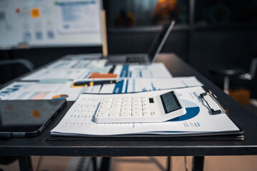 An empty office desk at night with a laptop displaying a business chart, balance sheet, loan...