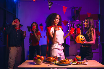 Asian friends, middle-aged man and young woman, enjoy Halloween office party with vampire costumes,...