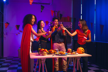Asian friends, middle-aged man and young woman, enjoy Halloween office party with vampire costumes, fried chicken, grilled food, grape wine, champagne, RGB lights, festive decorations in the night.