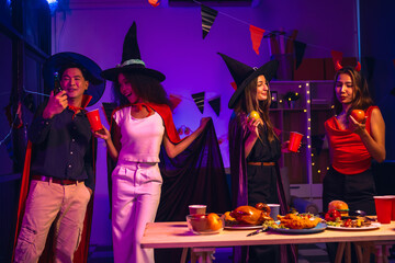 Asian friends, middle-aged man and young woman, enjoy Halloween office party with vampire costumes,...