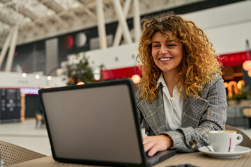 Successful and cheerful, a caucasian businesswoman takes notes, multitasks with her laptop, and...