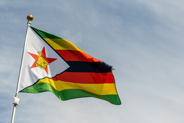 Flag of Zimbabwe, Zimbabwe, national symbol of Zimbabwe. Flag of Zimbabwe fluttering in blue sky. Independence Day. Flag of Zimbabwe, close-up. Great for news.