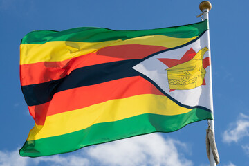Flag of Zimbabwe, Zimbabwe, national symbol of Zimbabwe. Flag of Zimbabwe fluttering in blue sky. Independence Day. Flag of Zimbabwe, close-up. Great for news.