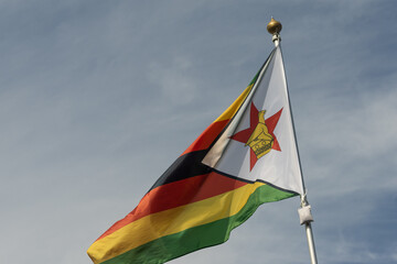 Flag of Zimbabwe, Zimbabwe, national symbol of Zimbabwe. Flag of Zimbabwe fluttering in blue sky. Independence Day. Flag of Zimbabwe, close-up. Great for news.