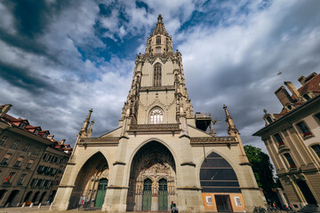 Explore the historic Gothic architecture of Bern’s Cathedral under dramatic cloud formations in Switzerland’s capital city