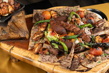 Delicious grilled meat with vegetable. Mixed grilled bbq meat with vegetables on wooden platter. Restaurant menu, dieting, cookbook recipe top view.