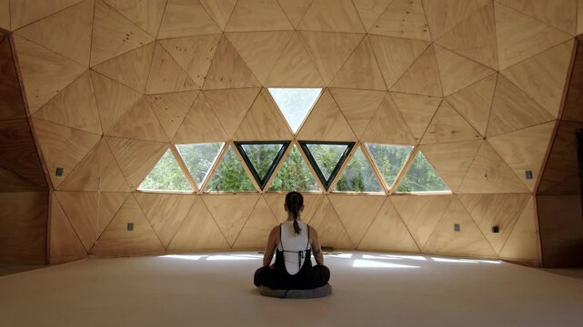 Wide angle harmonic centered view of single person in mindful yoga session with a Latina woman practicing in a tranquil geometric outdoor studio