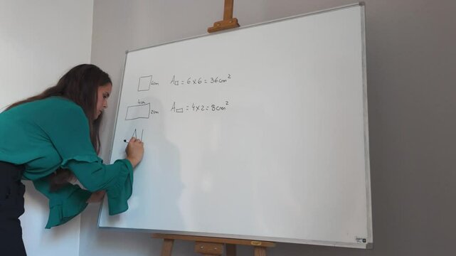 Woman teaches geometry formulas on a whiteboard in a classroom setting
