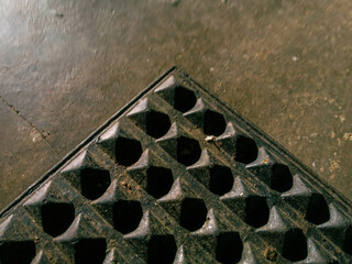 pattern of rubber mat like a pyramid on a cement floor. close up dirty black rubber doormat.