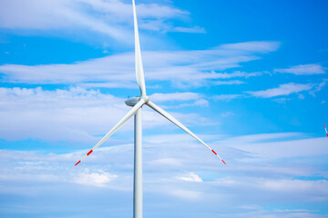 Obraz premium Fleet of power generators in motion. The blades of the wind farm rotate against the sky. The concept of extracting electricity from renewable sources. Wind turbine to generate electricity.