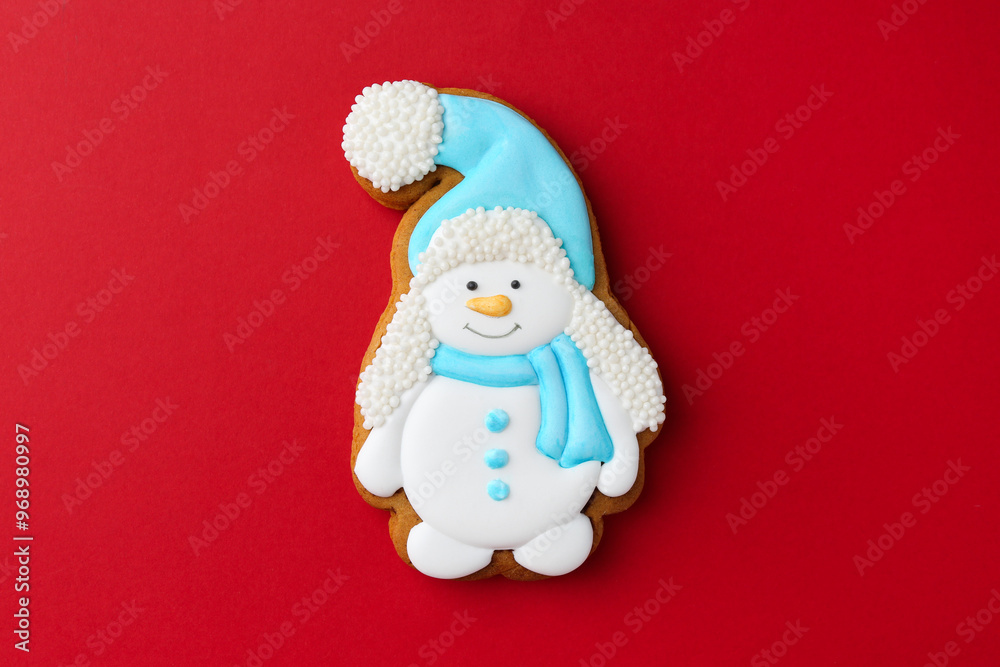 Wall mural Tasty Christmas cookie in shape of snowman on red background, top view