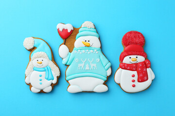 Tasty Christmas cookies in shape of snowman on light blue background, flat lay