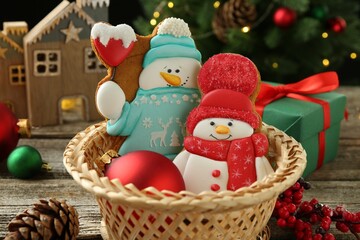 Delicious cookies in shape of snowmen and Christmas decor on wooden table, closeup