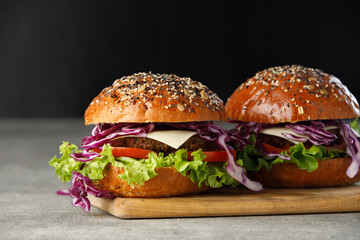 Two vegan burger with vegetables and sauce on dark background. Healthy food concept.