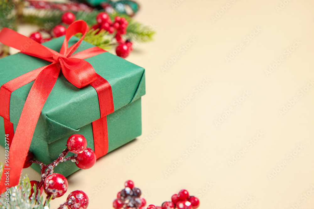 Wall mural christmas gift box, berries and fir tree branches on beige background, closeup. space for text