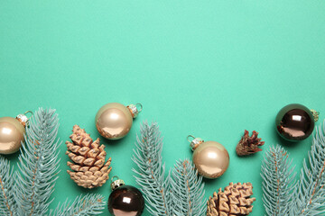 Christmas decor. Fir tree branches, cones and baubles on turquoise background, flat lay. Space for text