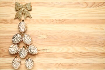 Shiny Christmas tree baubles and bow on wooden table, flat lay. Space for text