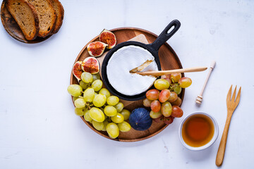 Fototapeta premium Baked camembert cheese in cast iron pan with fresh figs, grapes, and honey