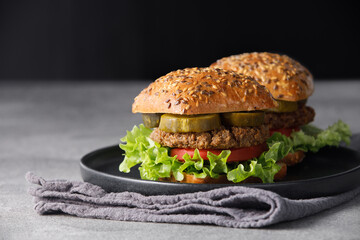 Two vegan burger with vegetables and sauce on dark background. Healthy food concept.