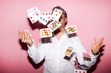 Man in a white shirt with lots of playing cards flying around him.