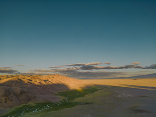 The view from the quadcopter to the desert, mountains and blue sky. The golden hour from a height in the desert.