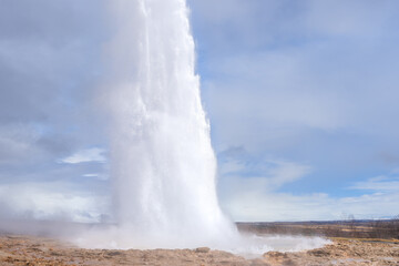 Tourists marvel at the Strokkur geyser erupting, sending a plume of steam and water high into the air. This geothermal wonder is a popular attraction in Iceland. Geysir Geothermal Area, Iceland.