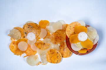 Top view of small mixed Masala and Plane Dal and Sabudana Papad Scattered on the white surface from a Kunke or a pot made by cane